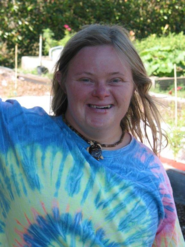 Smiling team member in blue tie-dye shirt outdoors in garden