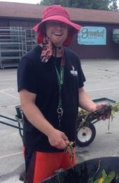 Team member in pink hat holding a bearded dragon at educational venue